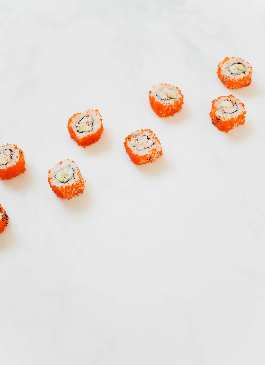 Rolls california con tobiko naranja sobre mármol claro
